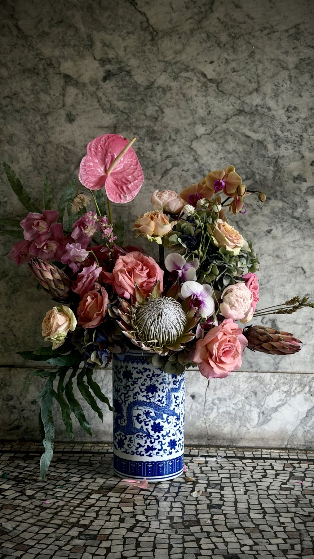 Sculptural dragon vessel holding a dramatic arrangement with protea